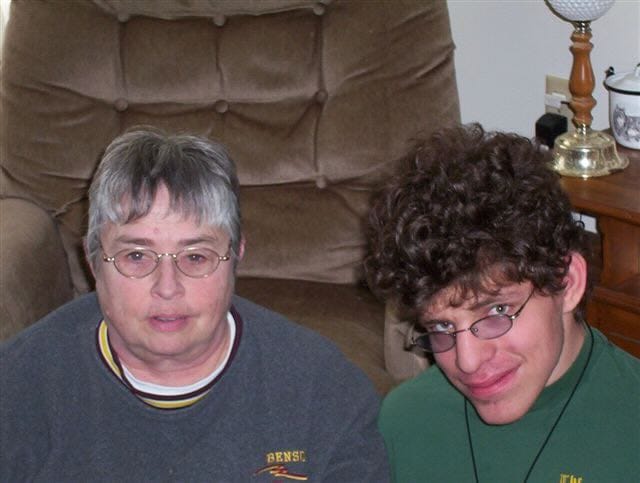 Grandma Marlys sitting next to Levi, both wearing glasses, in a cozy living room setting.