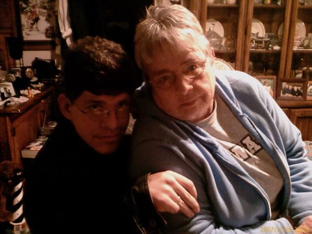 Grandma Marlys in a blue hoodie, resting her arm on her Levi's as they sit close together in a warmly lit home setting.