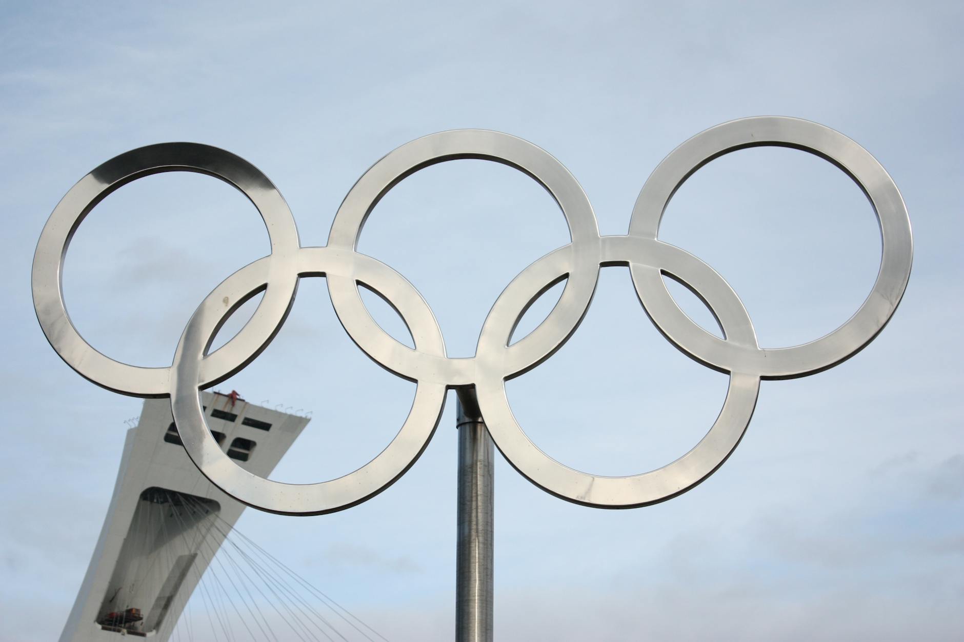 olympic rings with tower background under blue sky