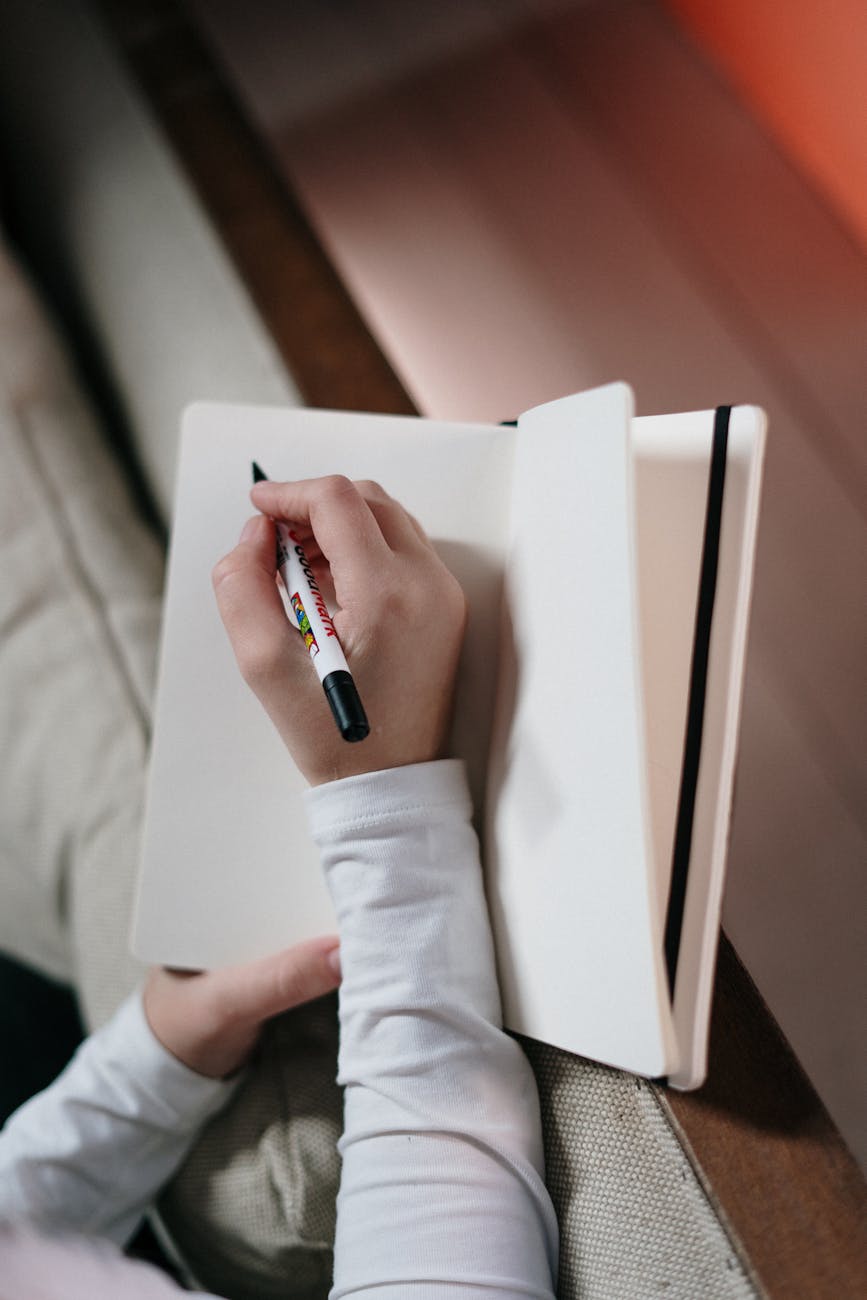 person in white long sleeve shirt holding pen and notebook